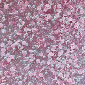Detailed close-up of pink cat paw polymer clay slices and mixed pearls for DIY crafts.