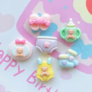 Nahaufnahme von bunten Harz Baby Charms, Miniatur Fläschchen und Lätzchen Haarschmuck DIY.