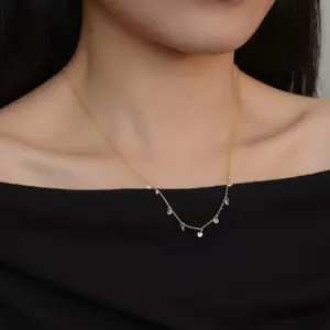 Detail view of dainty gold-plated silver clavicle chain necklace with sparkling zirconia pendants.