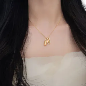 Close-up of the exquisite double pendant necklace with cultural motifs and shiny stones.