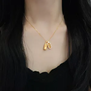 Close-up detail of the delicate gold chain featuring intricate traditional style dual pendants.