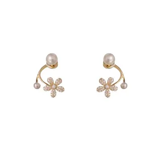 Primer plano de elegantes aretes de flor con piedras brillantes y perla, diseño delicado y fino.