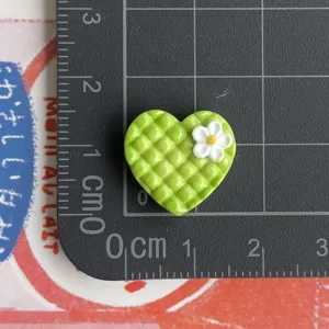 Detailaufnahme des kleinen grünen Karo-Herz Harz-Anhängers mit Blume auf Messraster.