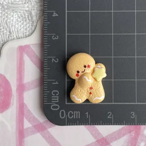 Resin gingerbread man charm detail view showing exact size on grid mat for DIY crafts.