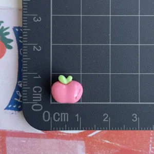Dettaglio charm mela in resina con griglia di misura per accessori nail art fai da te
