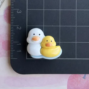 Detalle del tamaño del dije de pato de resina para funda de teléfono y pinza.