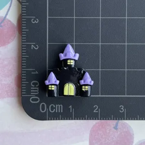 Close-up detail of Halloween purple castle resin charm for DIY phone case decoration.