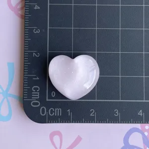 Pink sparkly resin heart charm detail view, cute DIY craft accessory for phone cases and hair clips.