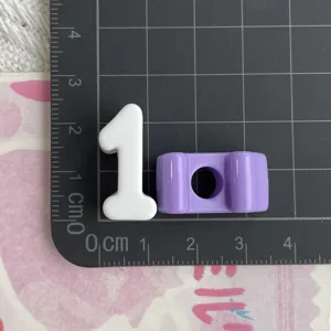 Primer plano detalle de cuenta de número de acrílico blanco y componente morado en estera.
