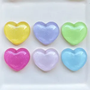 Close-up of colorful glitter heart resin charms, glossy finish for DIY crafts and phone cases.