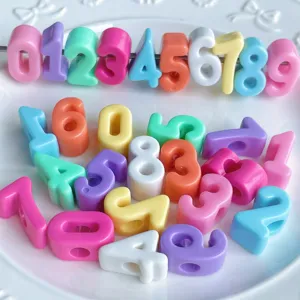 Primer plano de cuentas numericas acrilicas de colores con agujeros, ideales para joyeria y dijes.