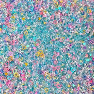 Close-up detail shot of mixed DIY craft beads, pearls, and sparkling heart sequins.