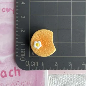 Primer plano detalle de accesorio de resina galleta huevo amarillo para funda de telefono DIY.
