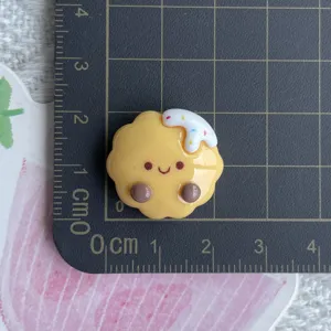Resin biscuit charm detail view, cute smiling face and cream decoration for DIY phone case.