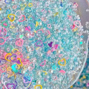 Close-up detail of mixed DIY resin charms, colorful beads, pearls, and rhinestones for crafts.