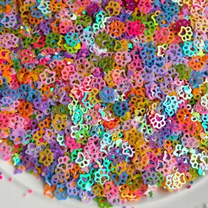 Primo piano dettagliato di paillettes colorate a forma di zampa per creazioni fai da te.