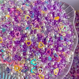Mixed purple bubble beads pearls rhinestones and colorful heart charms for DIY craft slime.