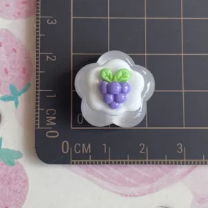 Detailed view of glossy resin grape flower DIY accessory showing size on cutting mat.