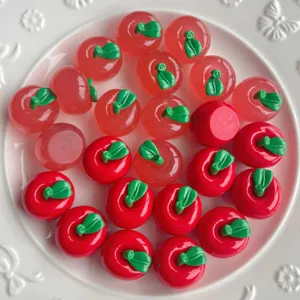 Dettaglio ravvicinato di ciondoli in resina a forma di mela rossa per cover e accessori fai da te.