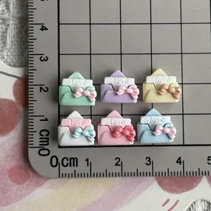 Mini resin envelope charms with cute bows and love text detail shot, ideal for DIY crafts.