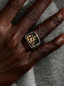 Close-up of vintage stainless steel sailing ship ring with golden galleon on black signet.