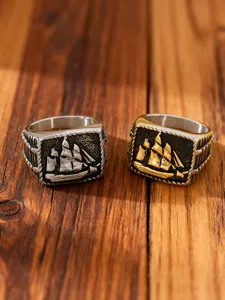 Detailed macro shot of vintage stainless steel sailing ship rings in silver and gold tones.