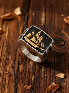 Close-up of vintage stainless steel ring featuring a golden sailing ship relief.