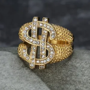Close-up of luxury gold hip-hop dollar sign ring with sparkling crystals on stone background