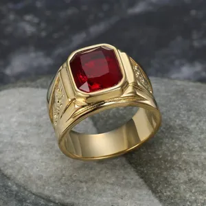 Detail of gold titanium steel ring featuring a large red gemstone and dragon engraving