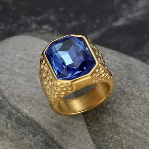 Detailed view of men's gold stainless steel ring with a large blue faceted gemstone