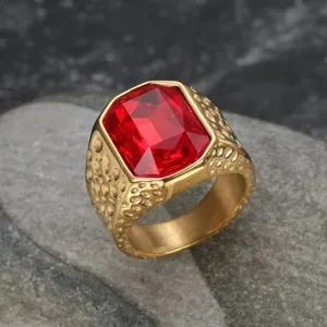 Macro detail of men's gold stainless steel ring featuring a large rectangular red zircon