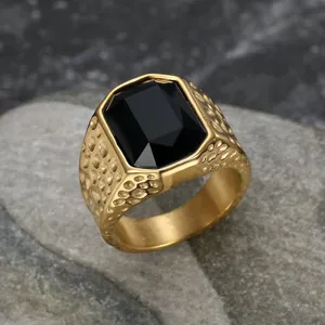 Detail of a gold-plated men's ring featuring a large black gemstone and hammered texture.