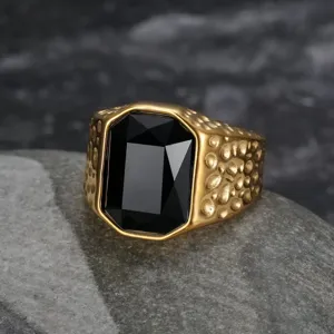 Macro detail of men's gold stainless steel ring featuring a large faceted black stone