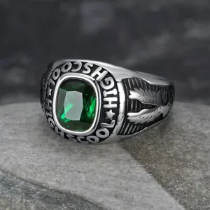 Macro view of vintage stainless steel eagle ring with emerald-cut green gemstone.
