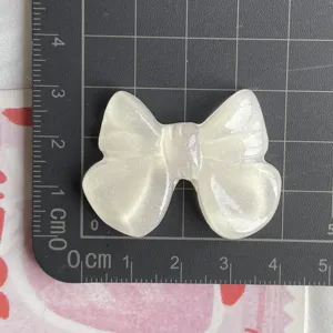 Primo piano di grande fiocco in resina trasparente glitterata, ciondolo per accessori artigianali.