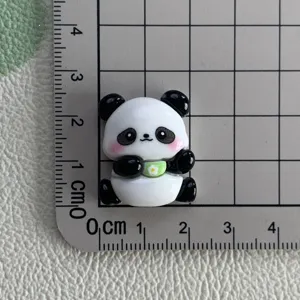 Close-up detail of cute resin panda charm with flower bowl on measurement grid, ideal DIY accessory.
