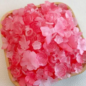 Dettaglio ciondoli fai da te in resina rosa, cabochon di rose e farfalle opache per cover telefono.