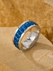 Close-up detail of a men's rotatable blue watch link stainless steel ring on natural stone.