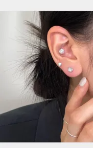 Detalle de primer plano de pendientes de tuerca de plata con cristales brillantes y finos.