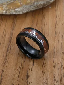 Macro view of black stainless steel ring with wood grain inlay and deer silhouette