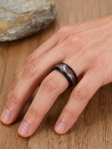Close-up of men's stainless steel ring with wood grain and reindeer forest silhouette on hand.
