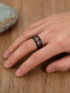 Macro detail of men's stainless steel ring featuring wood grain and golden deer landscape