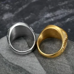 Detailed macro view of gold and silver Masonic cross stainless steel rings on stone.