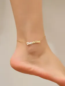 Detailed macro shot of gold-plated Old English 'Aquarius' zodiac sign anklet on ankle
