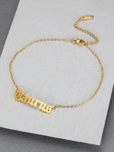 Close-up detail of golden titanium steel anklet featuring Taurus in Old English font
