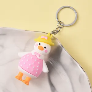 Cute cartoon duck keychain detail shot, featuring soft rubber duckling with pink dress and hat.