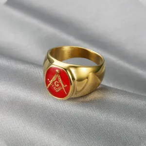 Macro detail view of a gold Freemasonry signet ring featuring a red enamel Masonic symbol.