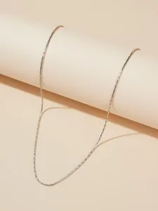 Close-up van een minimalistische zilveren titaniumstalen ketting op een beige achtergrond
