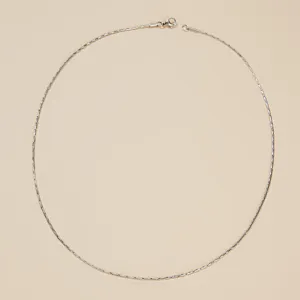 Minimalistische zilveren titanium stalen ketting van bovenaf gezien op beige achtergrond