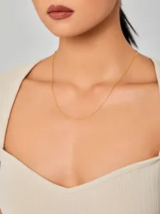 Detailopname van een minimalistische gouden titanium stalen ketting bij een vrouwelijk model